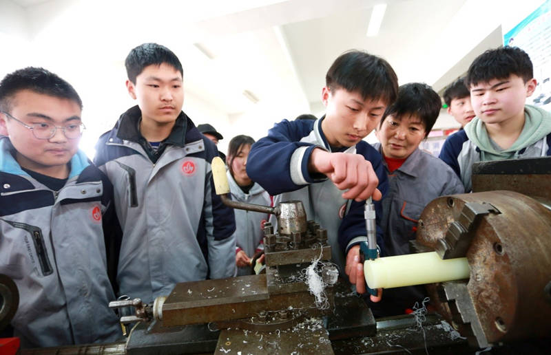 El 16 de marzo de 2021, los estudiantes aprenden a operar los tornos con su maestro en un taller en la Escuela de Tecnología de Donghai, provincia de Jiangsu, en el este de China. (Zhang Kaihu / Pueblo en Línea)