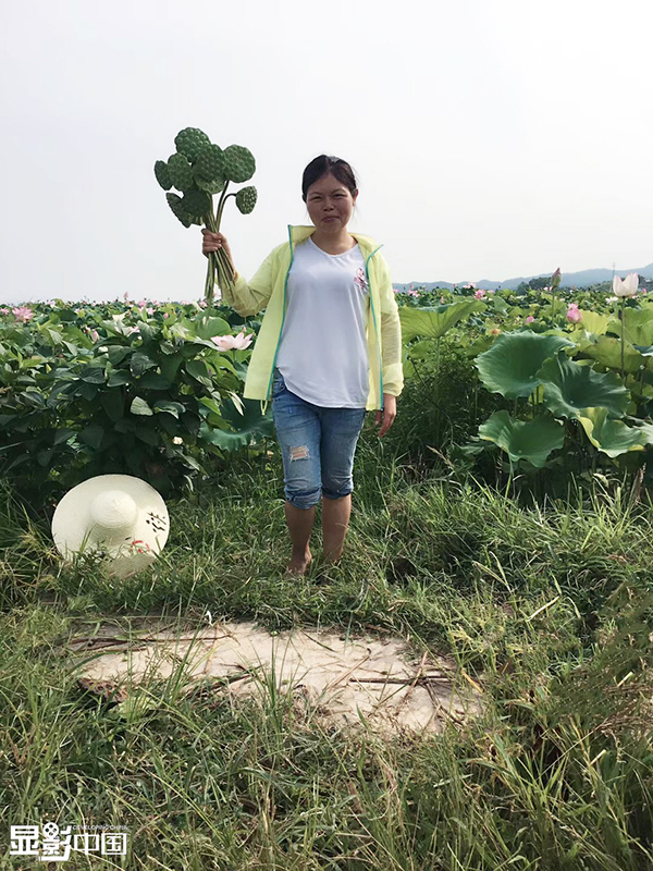 Rao Chunhong posa para fotos con semillas de loto. [Foto / Xinhua]