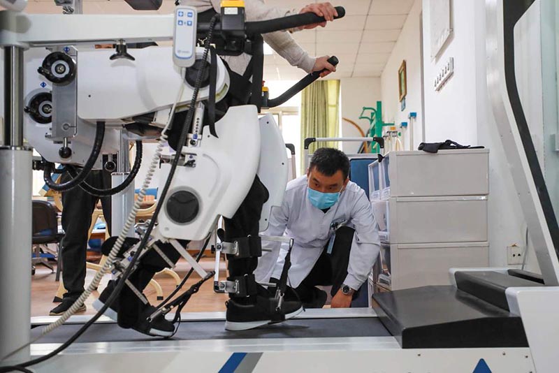 Los pacientes reciben terapia con un robot de rehabilitación de los miembros inferiores en el Hospital General de Aviación de la Universidad Médica de China en Beijing. [Foto de Zhang Jianfang / para chinadaily.com.cn]