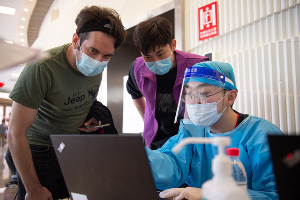 Un extranjero (izquierda) se registra para recibir una dosis de la vacuna Sinovac COVID-19 en un centro de vacunación en la Universidad de Tsinghua, Beijing, capital de China, el 3 de abril de 2021. (Foto: Xinhua)