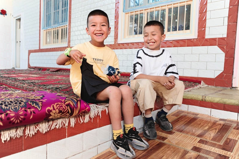 Abdurusul, de ocho años, juega con su mejor amigo en Kashgar, en la región autónoma Uygur de Xinjiang, en el noroeste de China, el 19 de mayo de 2021 (Pueblo en Línea / Kou Jie).
