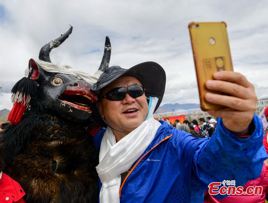 Un hombre se hace una foto con un yak fuera de la estación de Lhasa, en la región autónoma del Tíbet en el noroeste de China, el 26 de mayo de 2021. (Foto / Servicio de Noticias de China）