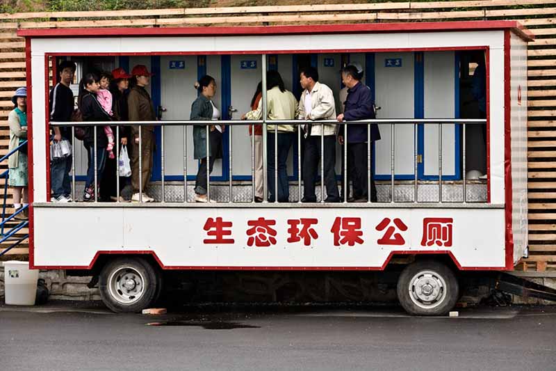 Los visitantes de la Exposición Mundial de Horticultura hacen fila para ir al baño en un "baño público ecológico" móvil en Shenyang, Liaoning, el 21 de mayo de 2006. [Foto proporcionada a China Daily]