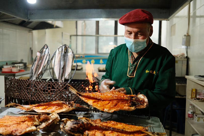 Un vendedor asa pescado en el mercado nocturno de la ciudad de Hotan, en la región autónoma Uygur de Xinjiang, en el noroeste de China, el 22 de mayo de 2021 (Pueblo en Línea / Zhang Ruohan).