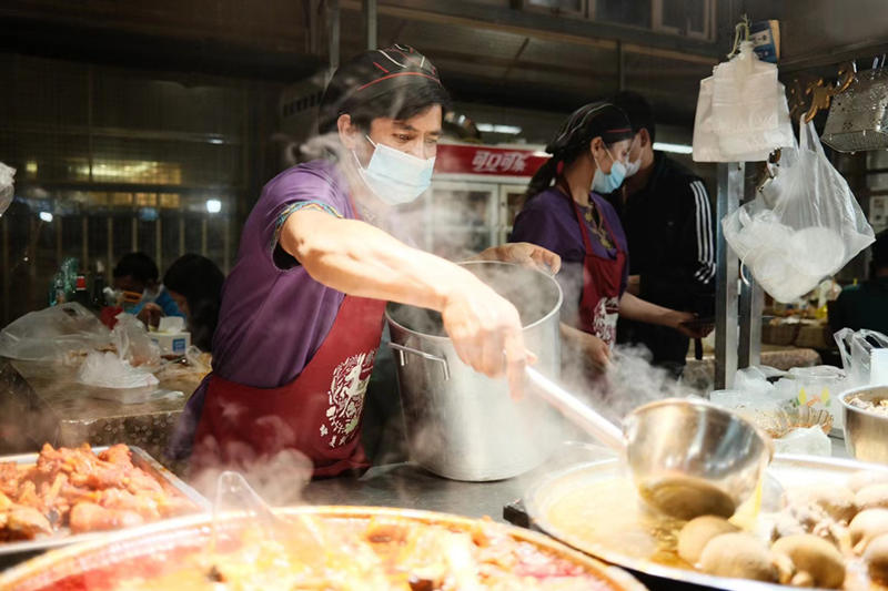 Un vendedor prepara delicias locales en un mercado nocturno en la ciudad de Hotan, en la región autónoma Uygur de Xinjiang, en el noroeste de China, el 22 de mayo de 2021 (Pueblo en Línea / Zhang Ruohan).