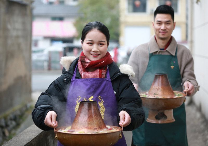 Dos camareros sirven una olla caliente en un restaurante del condado Chun'an en Hangzhou, provincia de Zhejiang, el 5 de enero de 2021. [Foto de Tang Jiakai / China Daily]