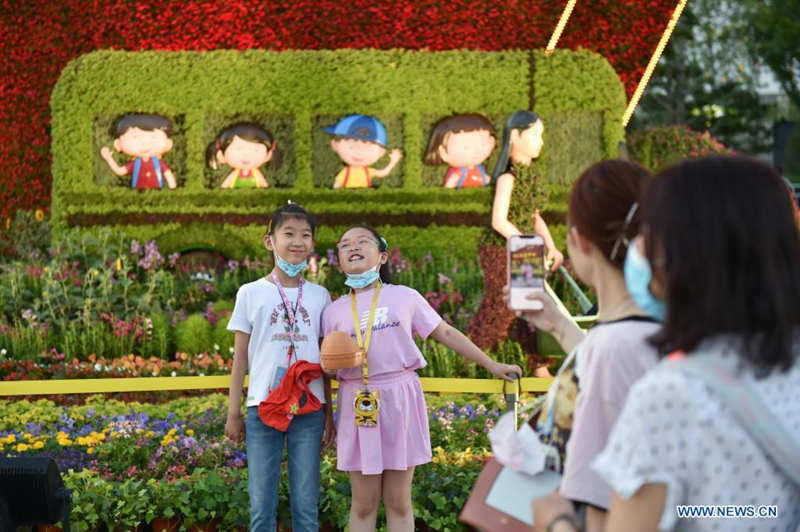 Niños posan junto a decoraciones florales que embellece la capitalina avenida Chang'an, 19 de junio del 2021. [Foto: Xinhua]