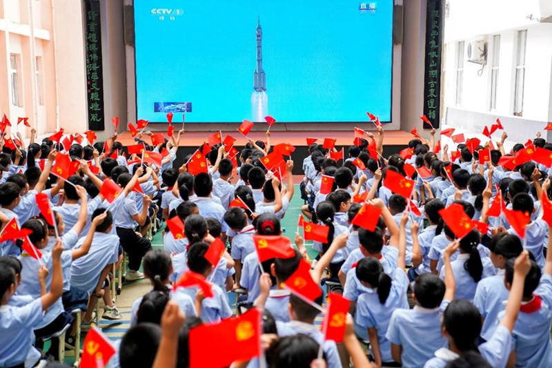 Estudiantes de primaria en Yuhuan, provincia de Zhejiang, ven en la tele en vivo el lanzamiento de la nave espacial Shenzhou-12, 17 de junio del 2021. (Foto: Pueblo en Línea/ Duan Junli)