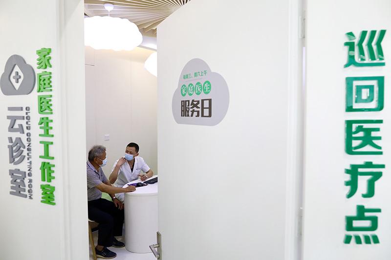Un médico ayuda a una persona de la tercera edad a buscar servicios a través de un sistema de telemedicina en una sala de consulta en la nube de un centro de salud pública de Yaozhuang, condado de Jiashan, en Jiaxing, provincia de Zhejiang, 13 de julio del 2021. [Foto: Zhu Xingxin/ China Daily]