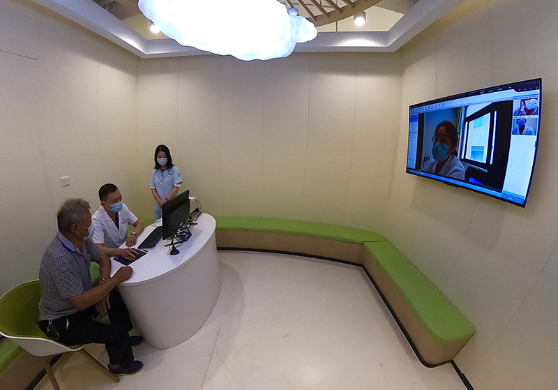 Un médico ayuda a una persona de la tercera edad a buscar servicios a través de un sistema de telemedicina en una sala de consulta en la nube de un centro de salud pública de Yaozhuang, condado de Jiashan, en Jiaxing, provincia de Zhejiang, 13 de julio del 2021. [Foto: Zhu Xingxin/ China Daily]