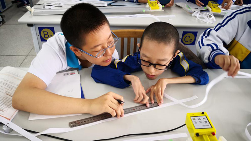 Xing Yifan (derecha) realiza un experimento de física en la escuela. [Foto proporcionada a chinadaily.com.cn]