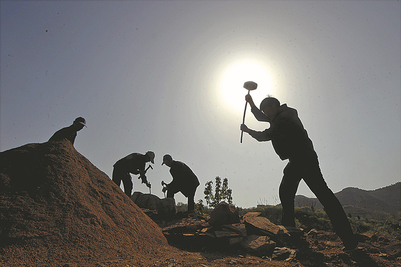 Feng (derecha) rompe piedras con un martillo para hacer material de construcción el 19 de abril. [Foto de Zhao Dongshan y Fu Youmin / para China Daily]