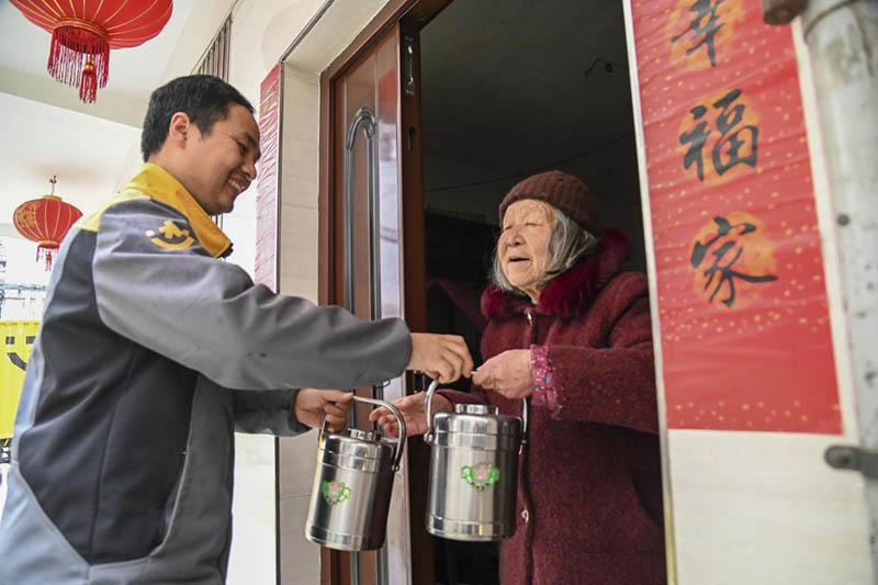Un empleado entrega voluntariamente comida a una anciana de la comunidad de Xuanhe, ciudad de Jinhua, provincia de Zhejiang, el 11 de marzo de 2021. Hu Xiaofei / Pueblo en Línea