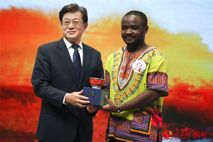 Li Xikui entrega el premio a la excelencia a Michael Mubaiwa, de Zimbabue, en la final del concurso "Los caracteres chinos y yo" 2021.