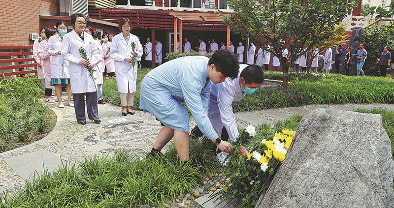 Qin Chuan (a la izquierda en la segunda fila) y los empleados del instituto asisten a una ceremonia para rendir homenaje a los animales de laboratorio el 30 de agosto. [ZHU XINGXIN / CHINA DAILY]