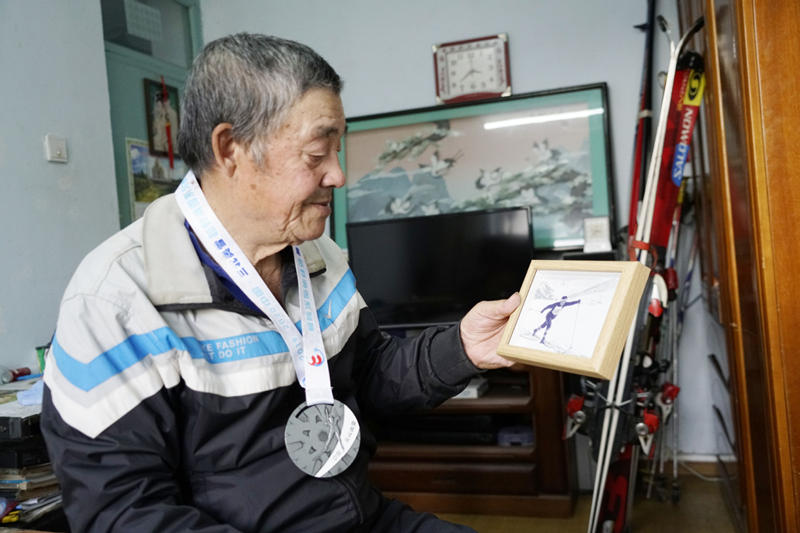 Han Tongyuan enseña una vieja foto donde aparece esquiando en su casa de Jilin. [Foto: Zhang Yichi/ China Daily]