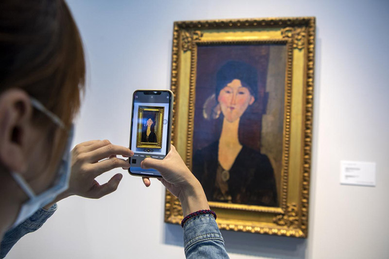 Un visitante hace fotos de una pintura del maestro italiano Amedeo Modigliani en el centro de exhibición de arte y reliquias culturales durante la IV Exposición Internacional de Importaciones de China (CIIE, por sus siglas en inglés) en Shanghai el 8 de noviembre de 2021. La última vez que la obra de arte se exhibió públicamente fue en 1973. (Pueblo en Línea / Weng Qiyu)