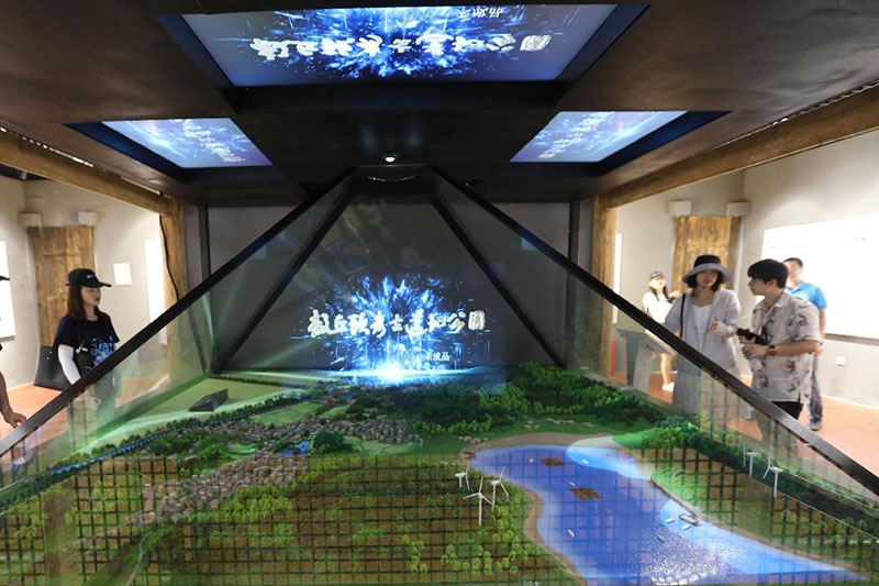 Los visitantes ven un modelo de un parque arqueológico con un proyector holográfico en un sitio arqueológico en Shangpan, Zona Experimental Integral de Pingtan, provincia de Fujian, el 19 de julio de 2021 (Pueblo en Línea / Xie Guiming).