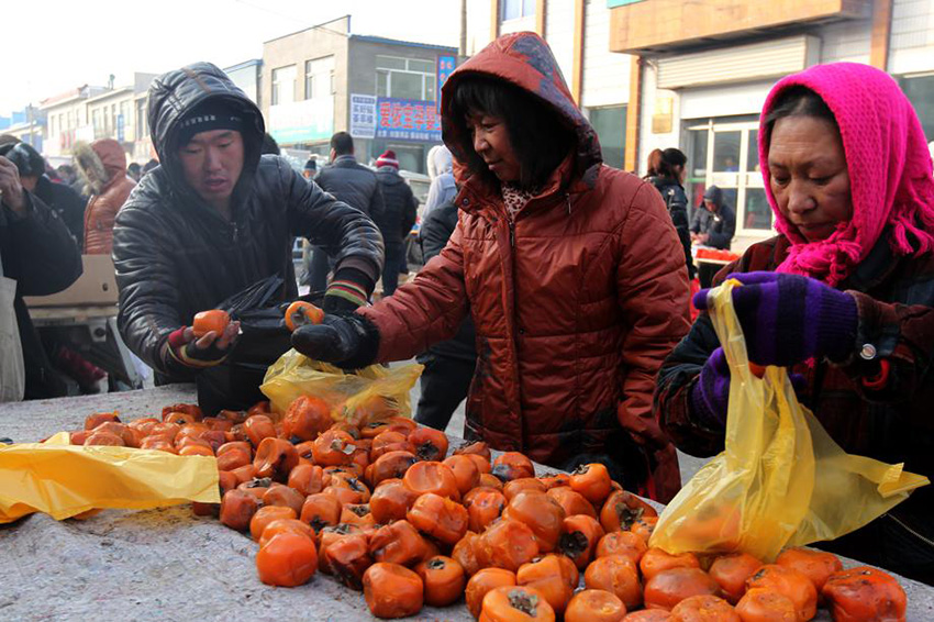 Los residentes compran caquis congelados en un mercado al aire libre en la provincia de Jilin. [Foto : Baishi/ Chinadaily.com.cn]