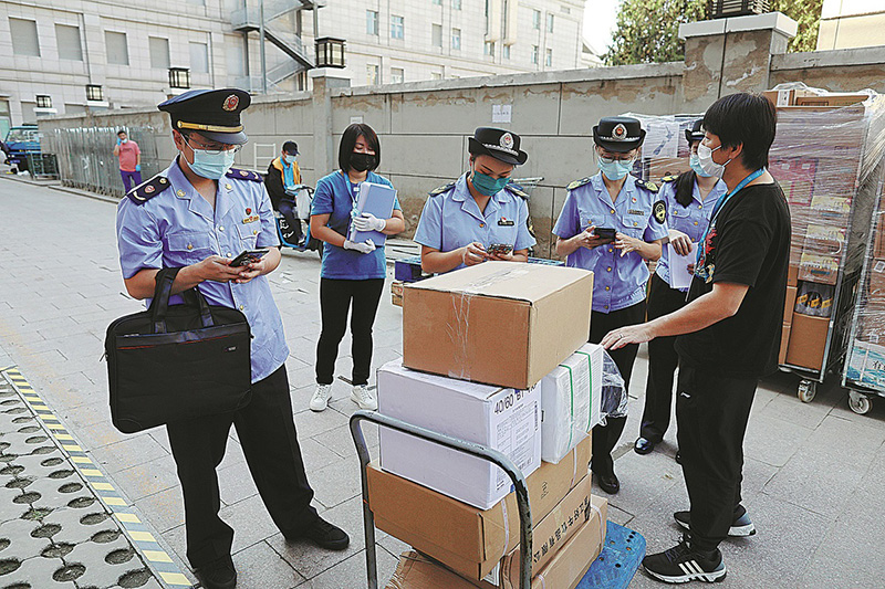 Los trabajadores de la Administración de Regulación del Mercado del Distrito de Fengtai verifican la información rastreable en cajas de alimentos congelados importados a la venta en un supermercado de Beijing, 29 de septiembre. (Foto: Zhu Xingxin/ China Daily)