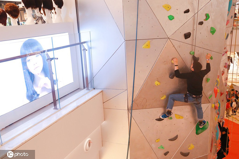 Los entusiastas de los deportes extremos experimentan la escalada en roca en un centro comercial de Shanghai, 19 de diciembre del 2021. [Foto: IC]