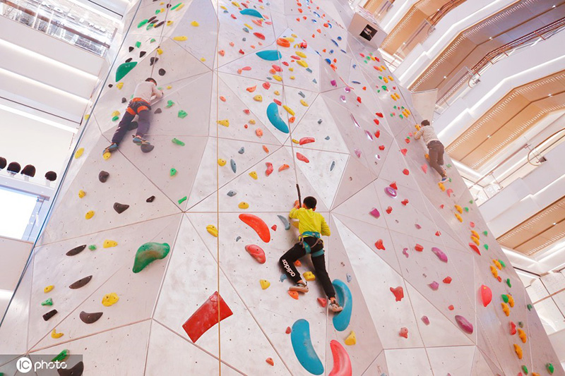 Los entusiastas de los deportes extremos experimentan la escalada en roca en un centro comercial de Shanghai, 19 de diciembre del 2021. [Foto: IC]