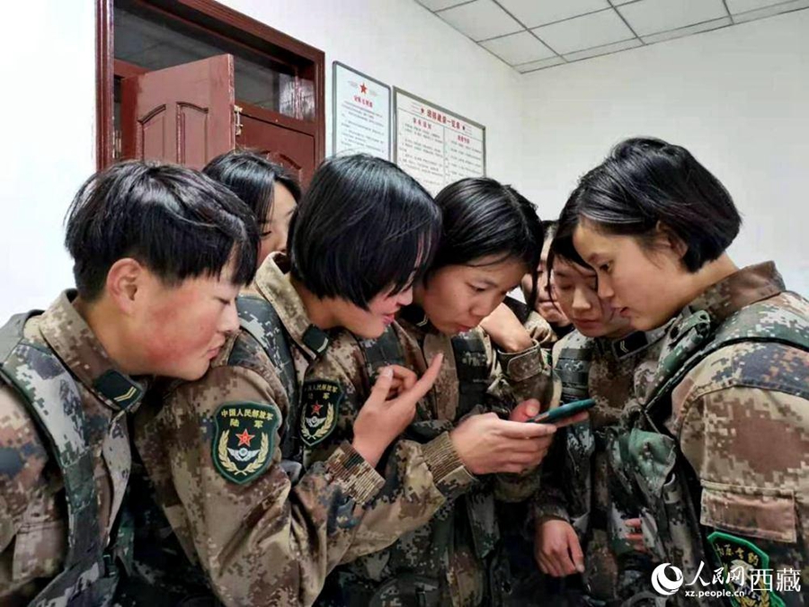 La foto muestra a mujeres soldados mirando fotografías de ellas mismas durante el entrenamiento. (Pueblo en Línea / Li Haixia)
