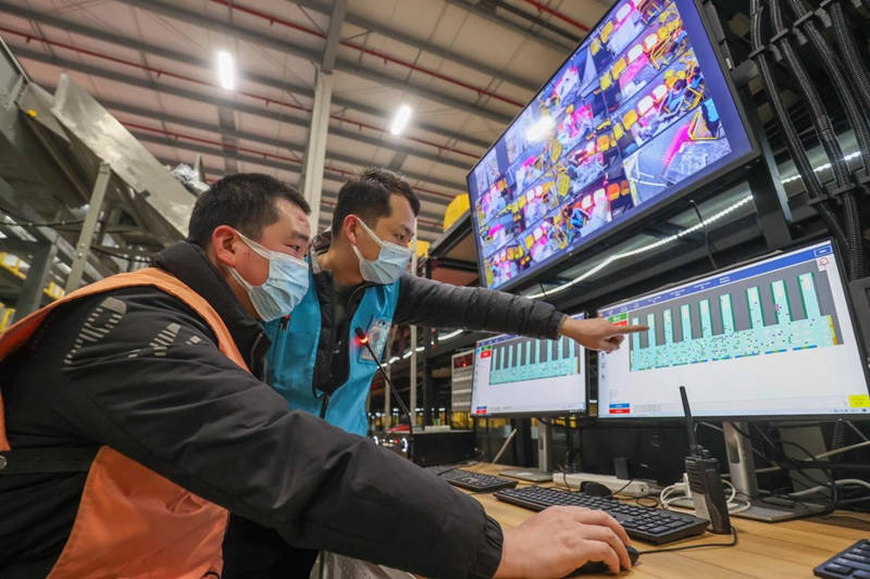 El 4 de enero de 2022, en el centro logístico de Kuaiyu Clothing Co., Ltd. en el Primer Parque Industrial de la Logística Inteligente del condado Deqing, ciudad de Huzhou, provincia de Zhejiang, los miembros del personal entregan los paquetes de mensajería exprés a los robots, conocidos cariñosamente como "personitas amarillas". Wang Shucheng/ Pueblo en Línea