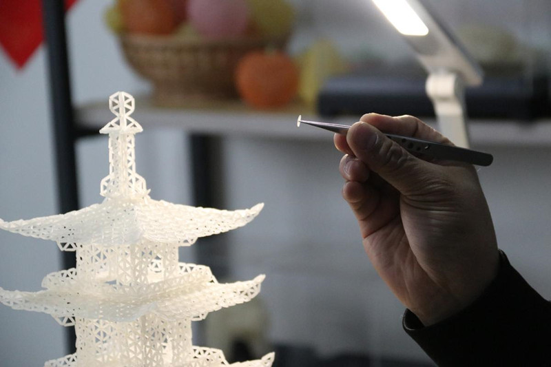 El artista popular Chen Guorui hace una pagoda usando alrededor de 12 500 granos de arroz. [Foto proporcionada a chinadaily.com.cn]