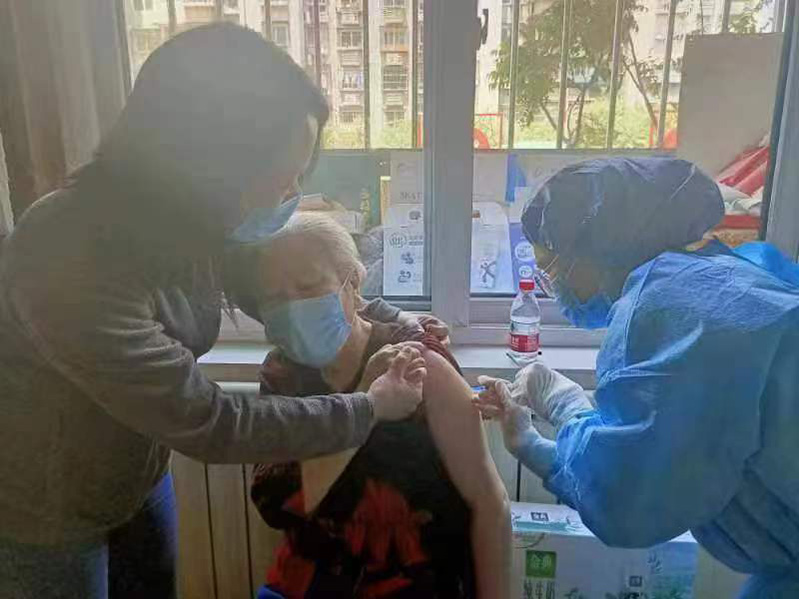 Una trabajadora social toma de la mano a una persona mayor durante una vacunación este sábado en Tianjin. [Foto: proporcionada a chinadaily.com.cn]