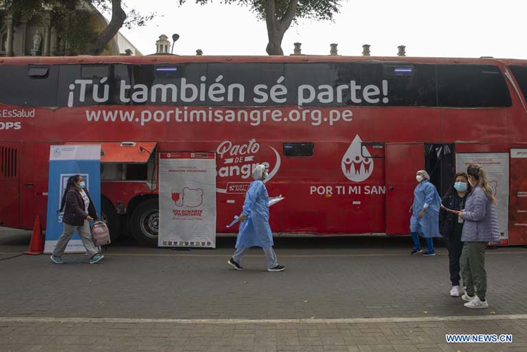 Trabajadoras de la salud caminan frente a un autobús donde se lleva a cabo una campaña de donación de sangre en el marco del Día Mundial del Donante de Sangre, en el distrito de Barranco, en Lima, Perú, el 14 de junio de 2022. El Día Mundial del Donante de Sangre se celebra anualmente el 14 de junio para agradecer a los donantes voluntarios no remunerados y concienciar de la necesidad de hacer donaciones regulares para garantizar la calidad, seguridad y disponibilidad de sangre y sus productos. (Xinhua/Mariana Bazo)