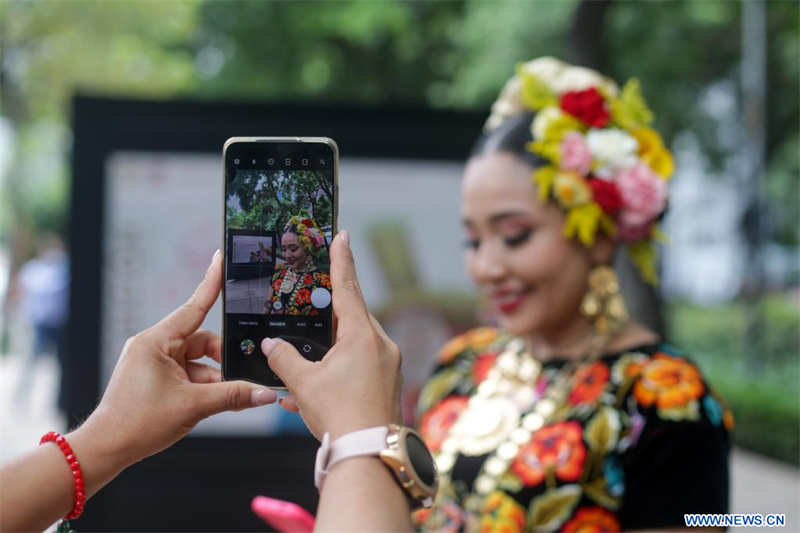 Una mujer toma fotografías con un dispositivo móvil durante la inauguración de la exposición "La Guelaguetza, Fiesta, Diversidad y Armonía", en la Ciudad de México, capital de México, el 4 de julio de 2022. (Xinhua/Francisco Cañedo)