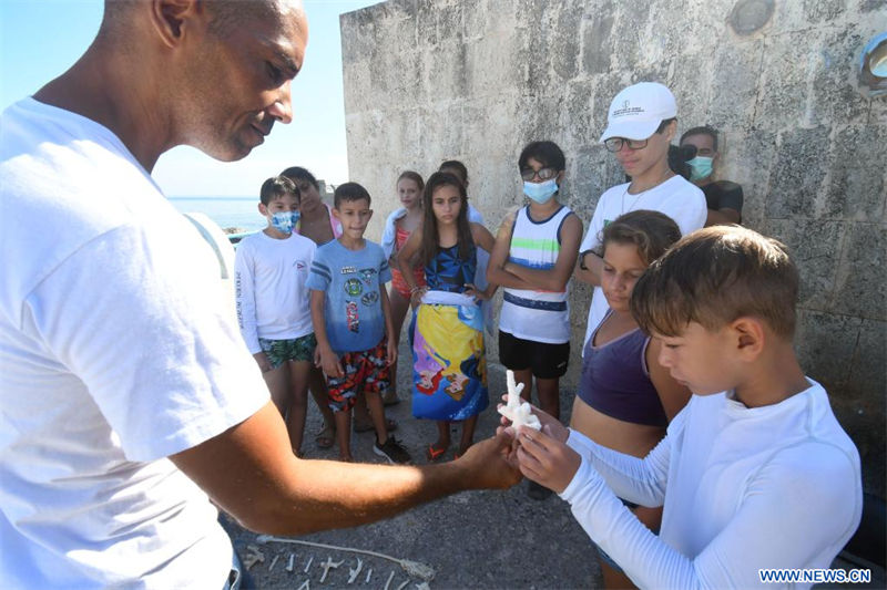  Imagen del 22 de julio de 2022 de un profesor mostrando a un niño un coral durante una clase de educación ambiental en el taller "Jardineros del Arrecife" en el Acuario Nacional de Cuba, en La Habana, capital de Cuba. Un proyecto de restauración de arrecifes mediante el cultivo, siembra y la reproducción sexual asistida de corales está en marcha desde este año en el Acuario Nacional de Cuba en La Habana. (Xinhua/Joaquín Hernández)