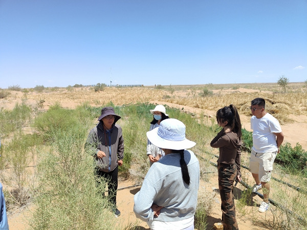 Zhu (izquierda) presenta el proyecto de desertificación de la Fundación SEE a los visitantes. [Foto proporcionada a China Daily]