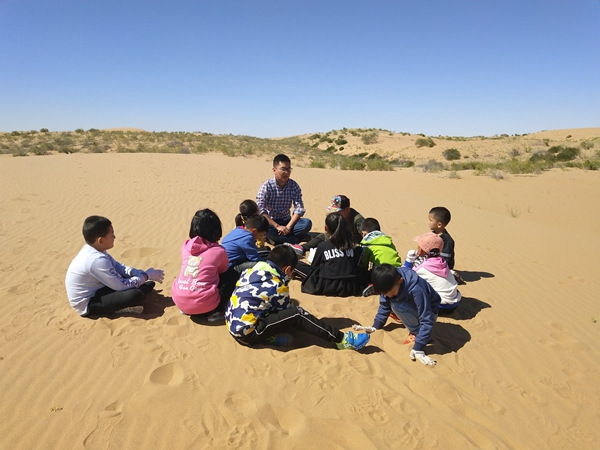 Zhu comparte su conocimiento sobre la desertificación y los árboles saxaul con los estudiantes. [Foto proporcionada a China Daily]