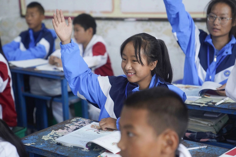 Los estudiantes levantan la mano para responder una pregunta en la clase de Su Zhengmin en una escuela secundaria en su ciudad natal, prefectura autónoma de Liangshan Yi, provincia de Sichuan. [Foto: proporcionada a chinadaily.com.cn]