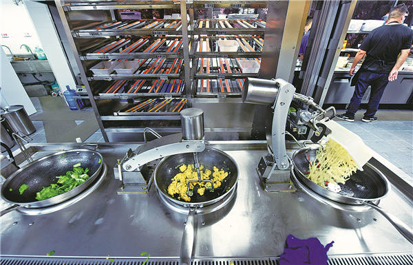 Los "chefs" robot preparan comida en un restaurante "inteligente" del distrito de Xihu, Hangzhou, provincia de Zhejiang, junio del 2023. El restaurante atrae a los clientes con platos elaborados por robots. [Foto: Long Wei / China Daily]
