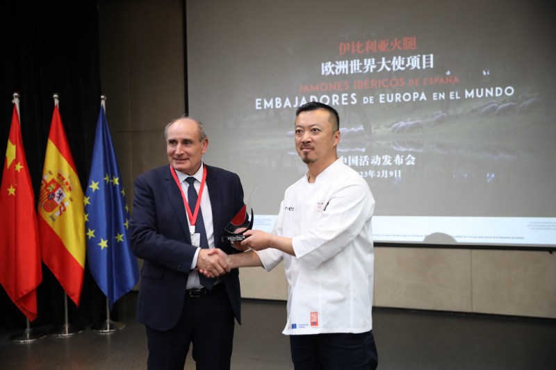 Antonio Prieto, presidente de ASICI, entrega un reconocimiento como Embajador del Jamón Ibérico en China al chef chino Irven Ni durante la presentación de la campaña “Jamones Ibéricos de España, Embajadores de Europa en el Mundo”, Instituto Cervantes, Beijing, 9 de febrero del 2023. (Foto: YAC)