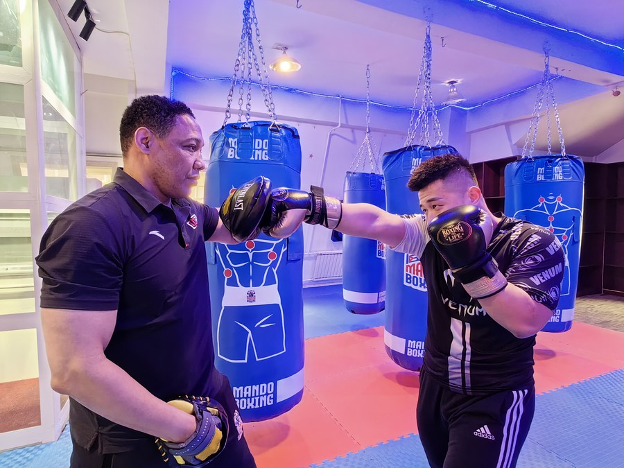 Armando (izquierda), entrenador de boxeo cubano, en un entrenamiento con un boxeador. (Xinhua/Wang Junbao)