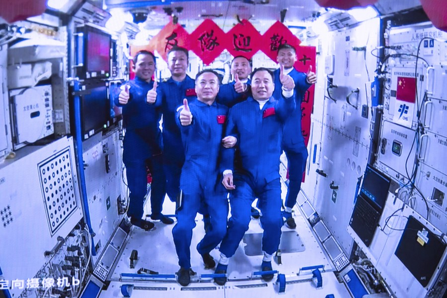 Esta imagen de pantalla, capturada en el Centro de Control Aeroespacial de Beijing el 30 de mayo de 2023, muestra a las tripulaciones de las misiones espaciales Shenzhou-15 y Shenzhou-16 en una foto grupal en el interior del módulo central Tianhe de la estación espacial de China. (Xinhua/Han Qiyang)