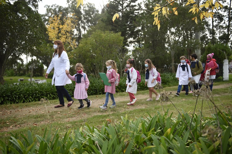 Niños ingresan junto a su maestra a una escuela rural, en la localidad de Migues, en el departamento de Canelones, Uruguay, el 3 de mayo de 2021. (Xinhua/Nicolás Celaya)