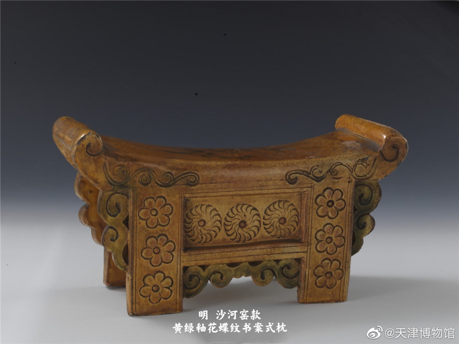 Una almohada vidriada de color amarillo verdoso con motivos florales y de mariposa en estilo estantería, creada durante la dinastía Ming. [Foto: Cuenta oficial de Weibo del Museo de Tianjin]