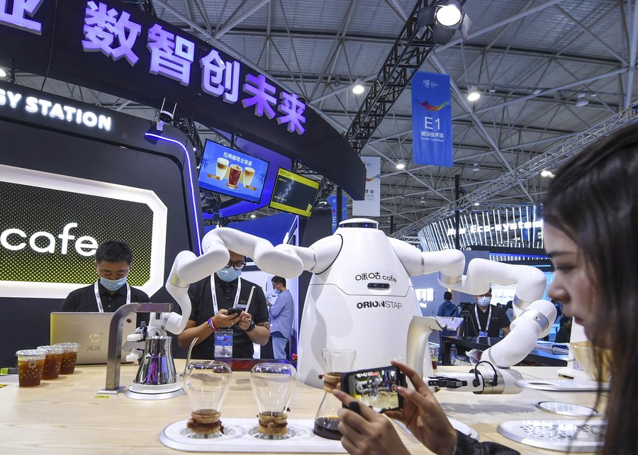 Una visitante toma fotografías de un robot alimentado con Inteligencia Artificial que prepara café durante la Exposición Internacional de la Industria de Macrodatos de China 2021, en Guiyang, provincia de Guizhou, en el suroeste de China, el 26 de mayo de 2021. (Xinhua/Yang Wenbin)