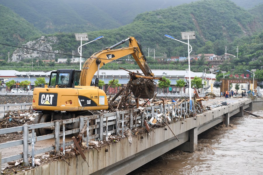 Una excavadora retira escombros y basura de un puente en la aldea Shuiyuzui, en el distrito de Mentougou, afectado por las inundaciones, en Beijing, capital de China, el 1 de agosto, 2023. (Xinhua/Ju Huanzong)
