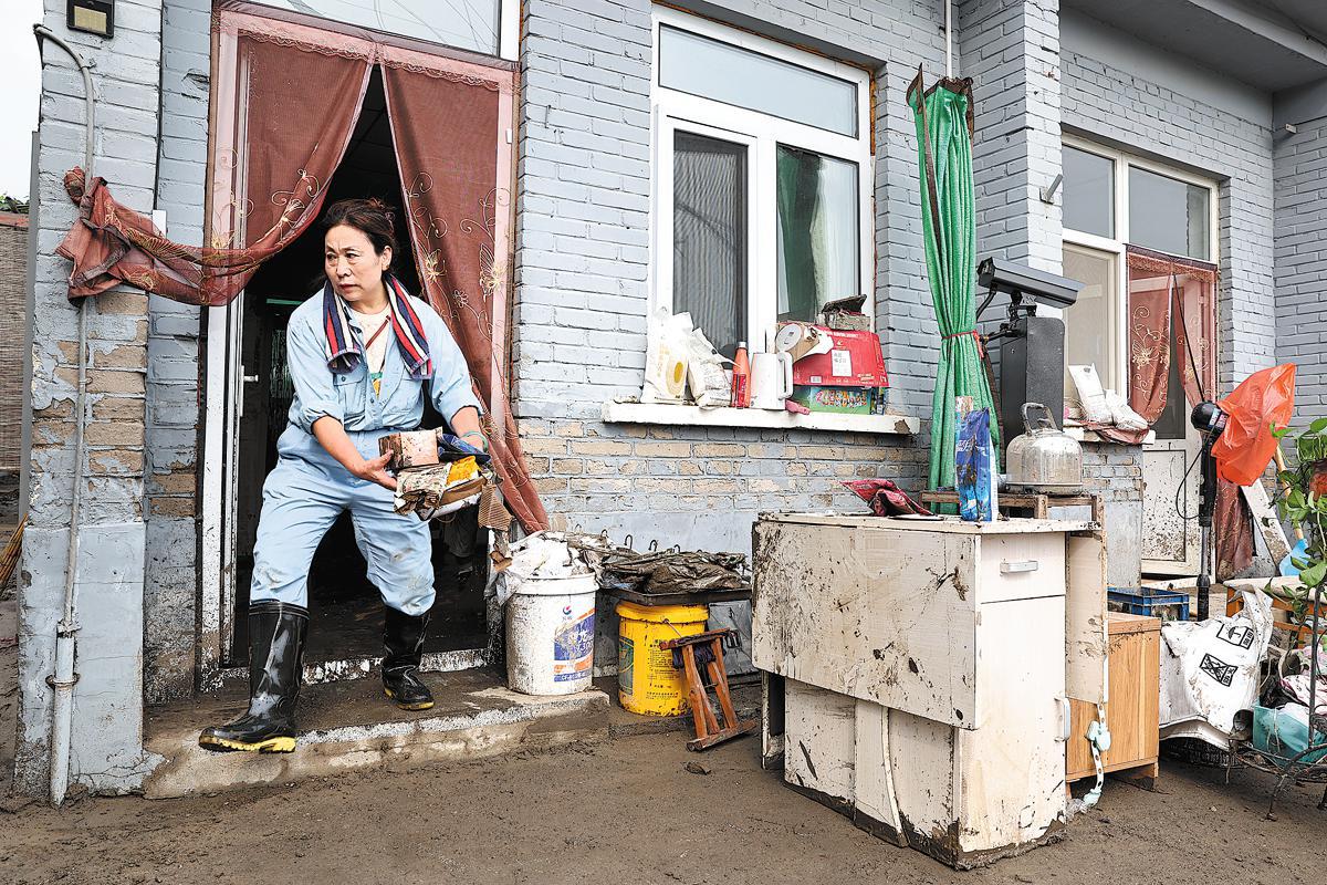 Una residente del distrito Fangshan de Beijing, cuya vivienda sufrió graves inundaciones, ordena sus pertenencias el miércoles después de evacuar el agua. Feng Yongbin / China Daily
