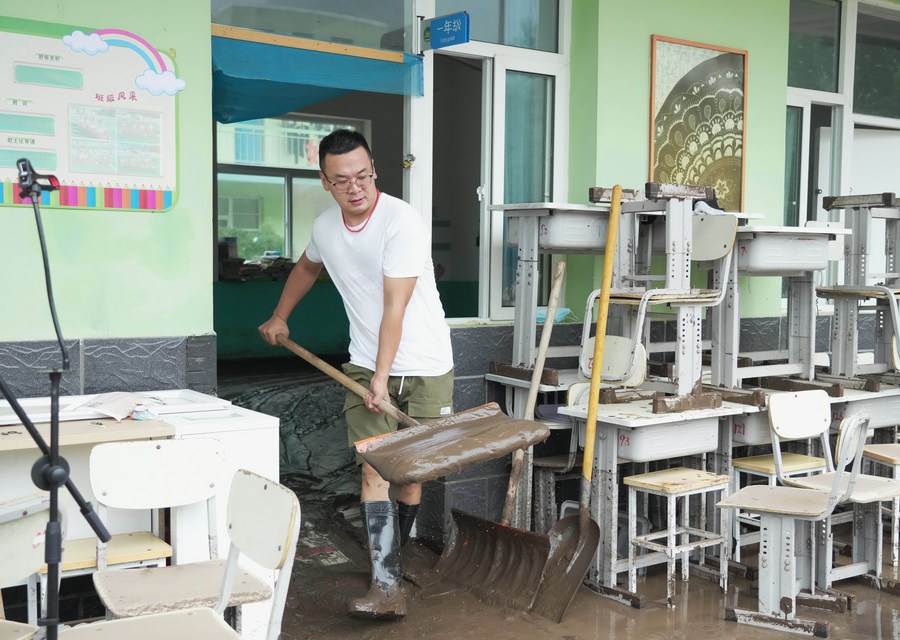 Un maestro limpia lodo en una escuela, en el poblado de Qizhongkou del distrito de Laishui, en la provincia de Hebei, en el norte de China, el 11 de agosto de 2023. (Xinhua/Wang Kun)