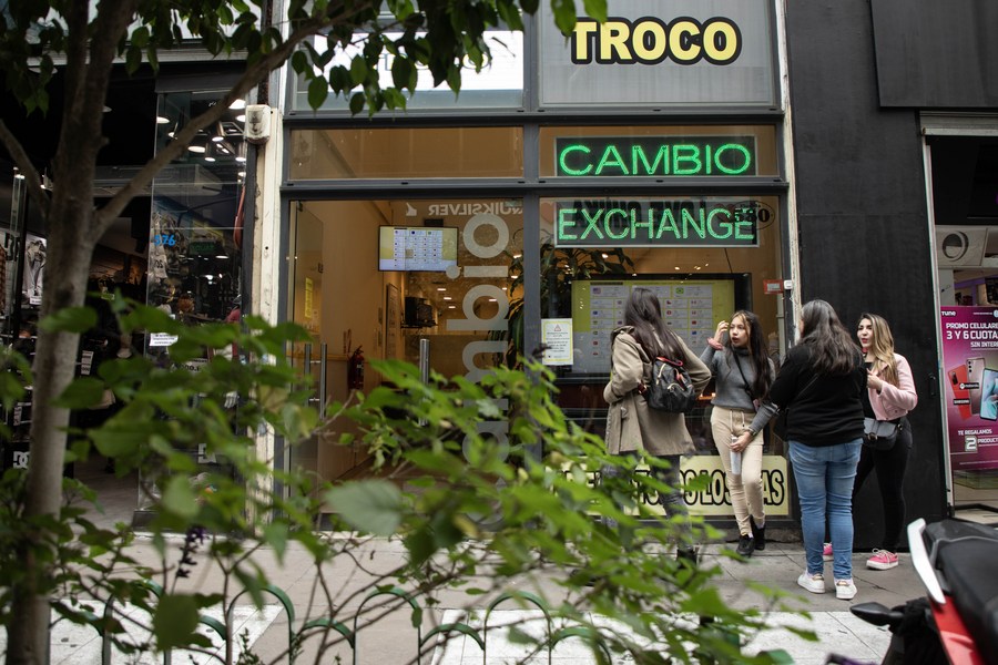 Personas conversan frente a un local de venta de divisas ubicado en el Microcentro, zona financiera de la ciudad de Buenos Aires, capital de Argentina, el 10 de agosto de 2023. (Xinhua/Martín Zabala) 