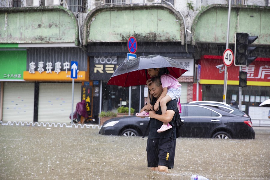 Un hombre que lleva a su pequeña en hombros cruza una calle inundada en el distrito de Panyu de la ciudad de Guangzhou, en la provincia sureña china de Guangdong, el 8 de septiembre de 2023. (Xinhua/Li Jiale)