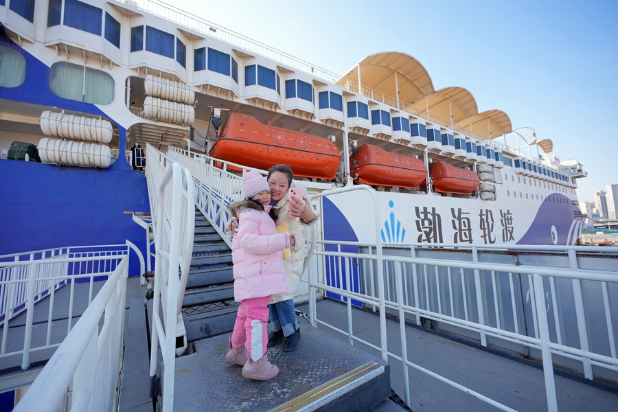 Pasajeras se toman una foto antes de abordar un barco en el puerto de Yantai, provincia de Shandong, en el este de China, el 15 de febrero de 2023. (Foto de Tang Ke/Xinhua)