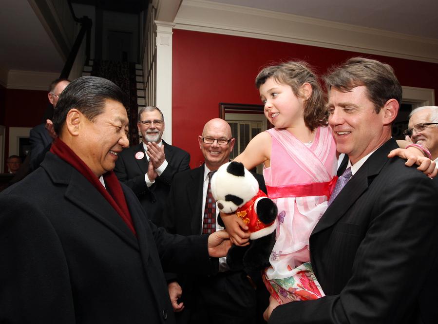 Xi Jinping (i) regala a la nieta de su vieja amiga Sarah Lande un muñeco de panda en Muscatine, una pequeña ciudad de Iowa, Estados Unidos, el 15 de febrero de 2012. (Xinhua/Lan Hongguang)